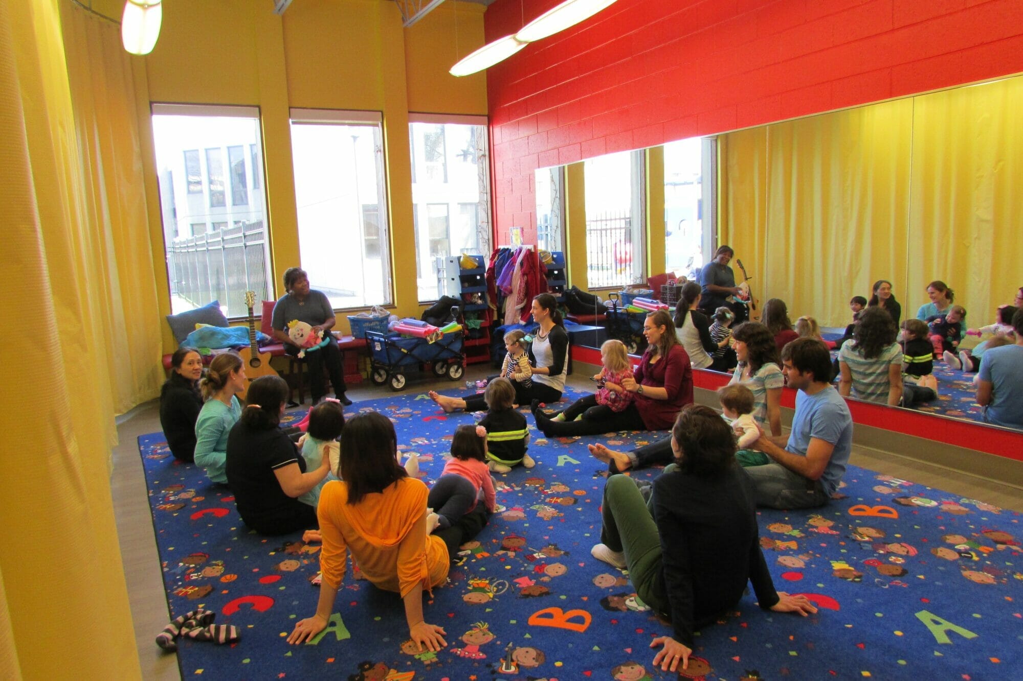 People sit in a circle with their children for an activity.