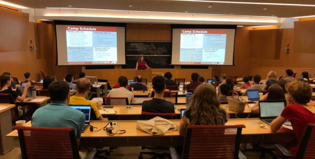 A photograph of a Saieh Hall Lecture Hall, full of grad students seated and in discussion during the Academic Job Market Summer Camp in 2019. 