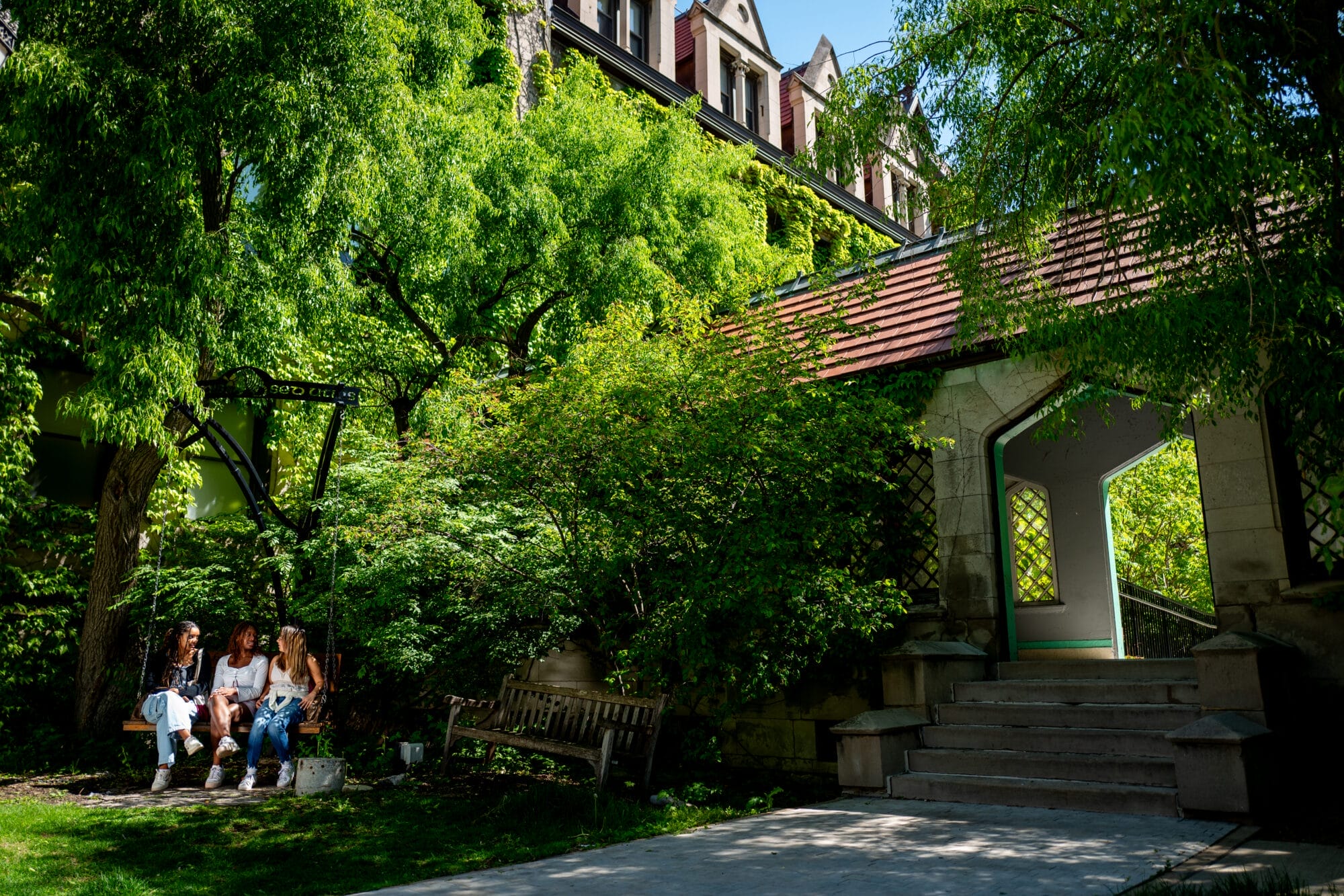 Nook on the campus quad, students chat on a bench. Photo by Stephen Garrett.